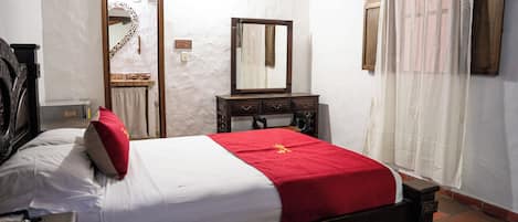 A bedroom with a bed, a dresser, a mirror, and a door.