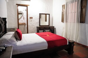 A bedroom with a bed, a dresser, a mirror, and a door.