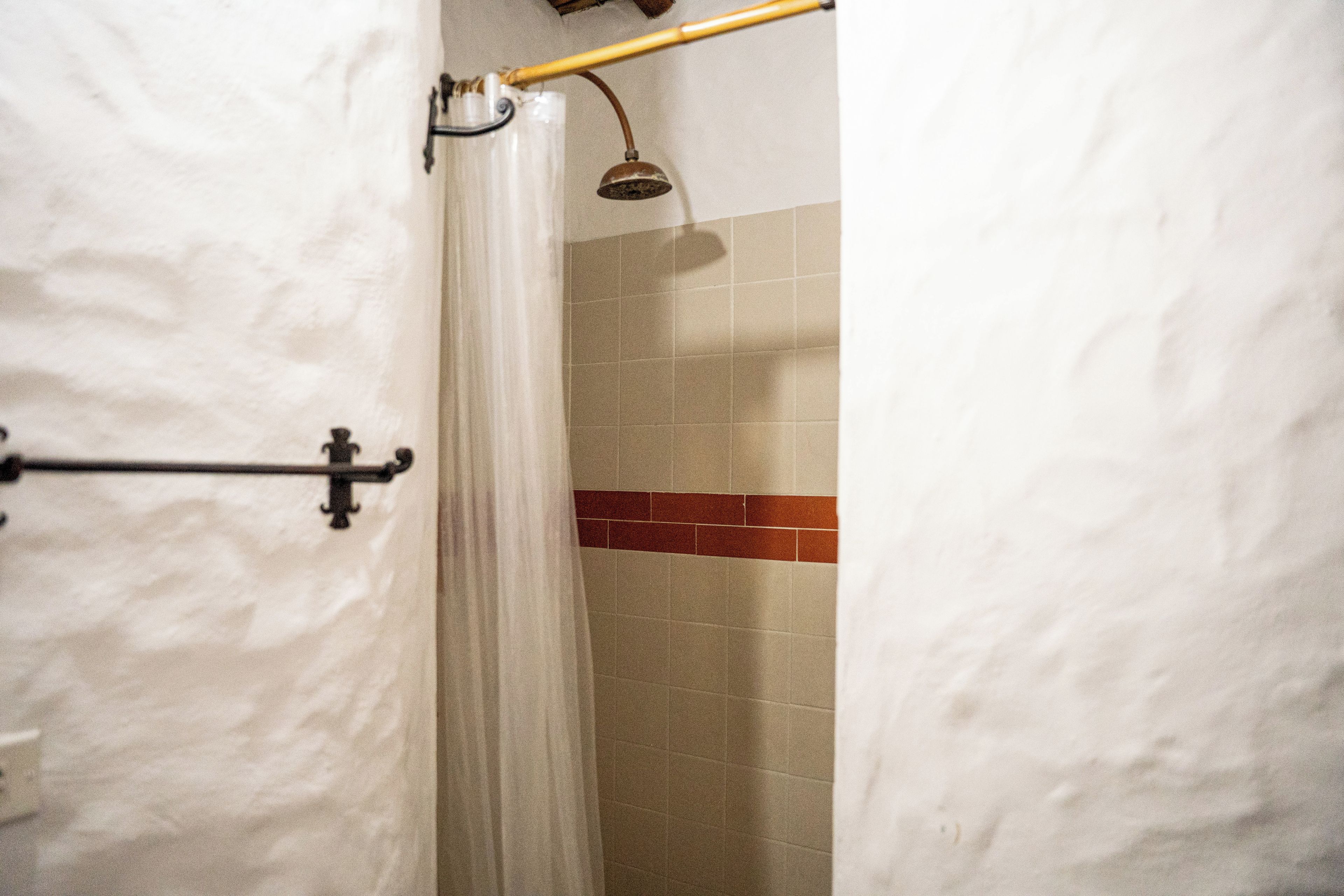Un baño con cortina de ducha, toallero y paredes de azulejos.