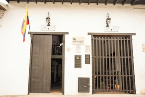 A building entrance with two doors, each marked with a number, and a flag to the left. - Hotel Boutique Macaregua Giron (Giron)