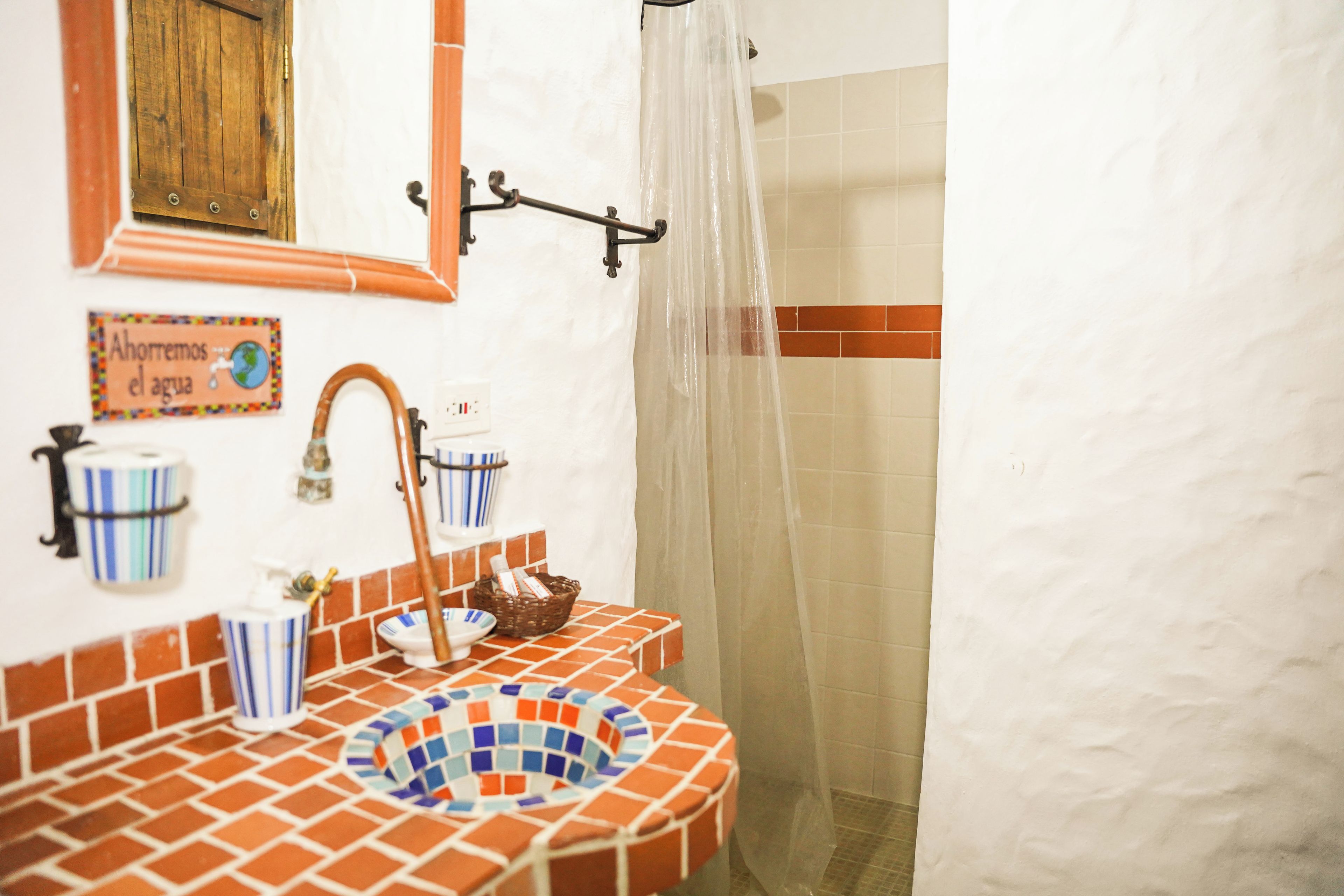 Un baño con lavamanos azulejado, cortina de ducha y toallero de pared.