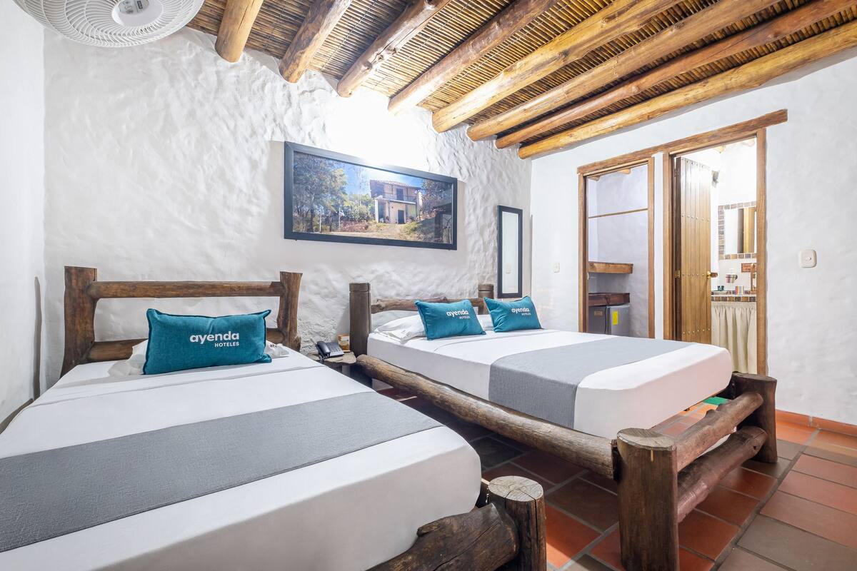 A hotel room with two beds, wooden headboards, and a large window with a view of a building.