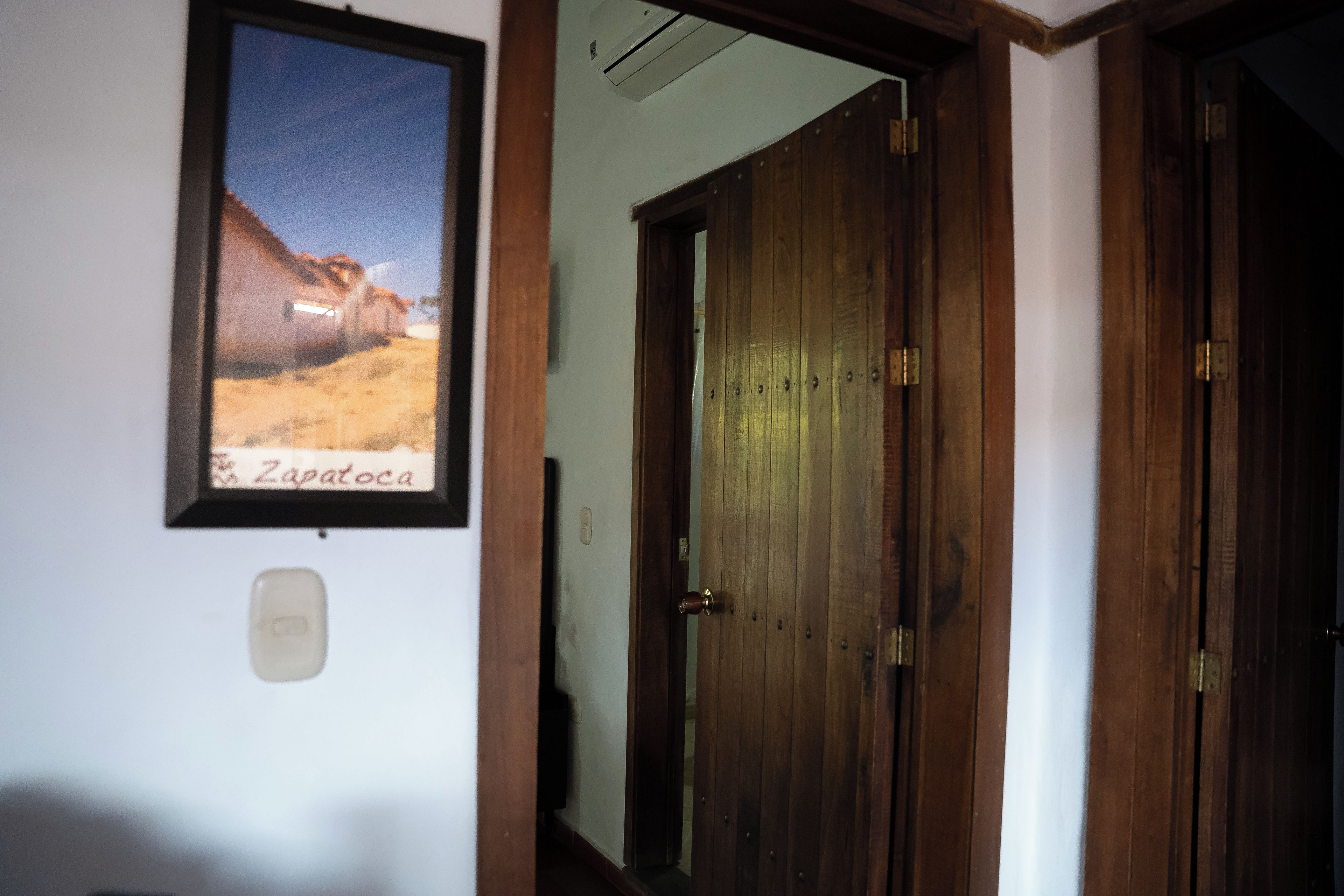 A hallway with a wooden door and a framed picture on the wall.