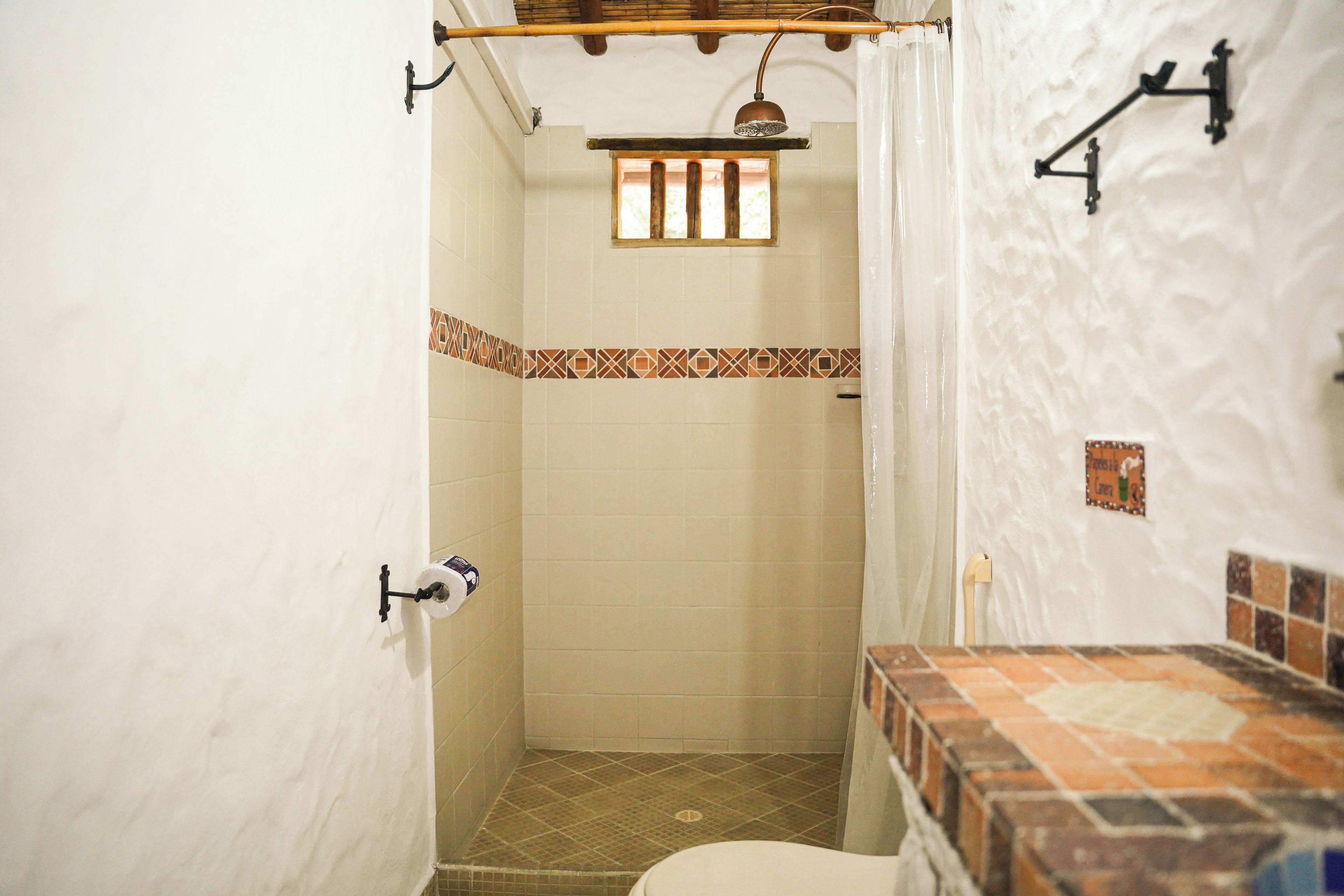 Un baño con ducha, inodoro y toallero.