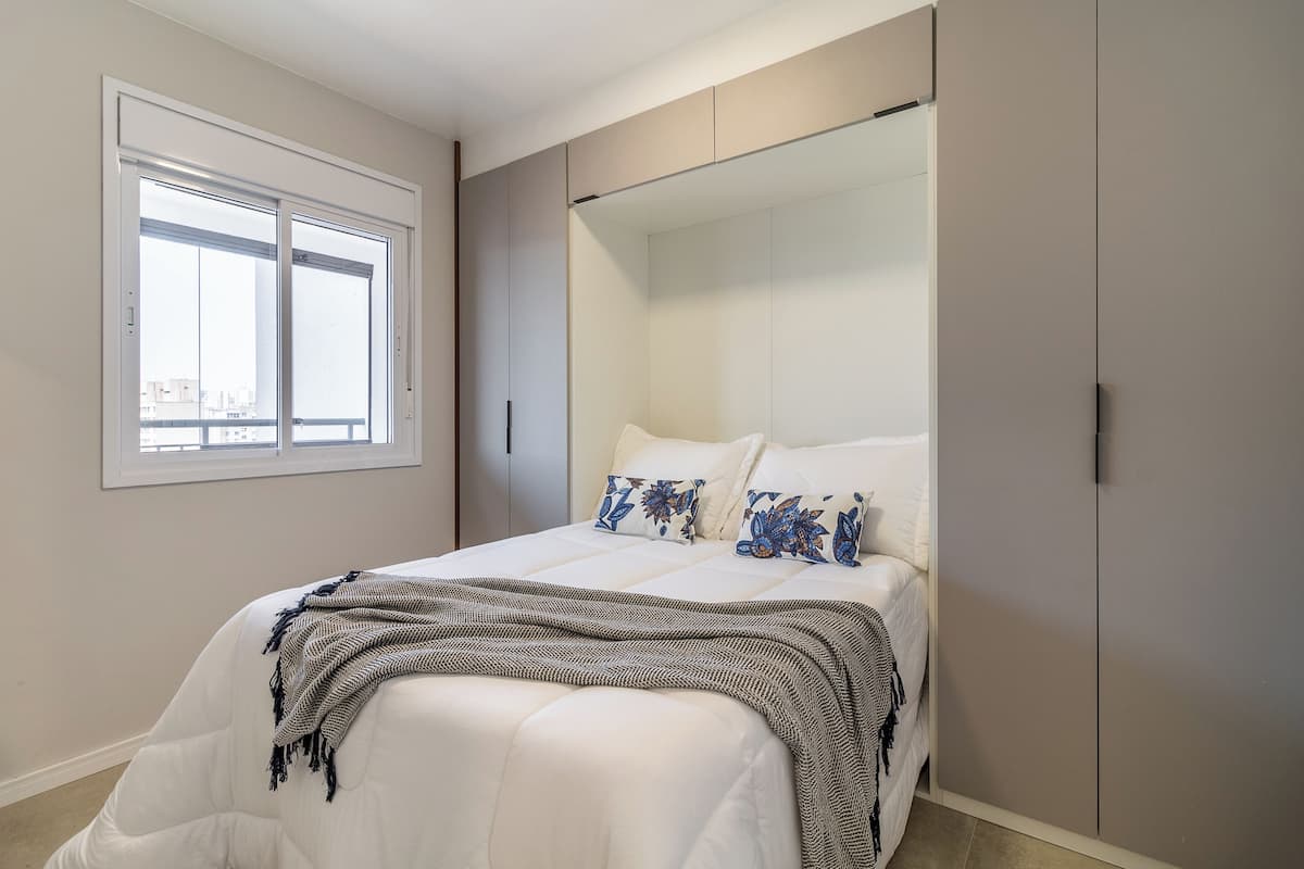 A bedroom with a bed, a window, and a wardrobe.