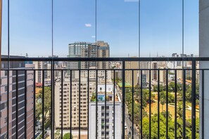 A high-rise building with multiple floors, large windows, and a view of a cityscape through a window with vertical blinds. - Akile Central Park (São Paulo)