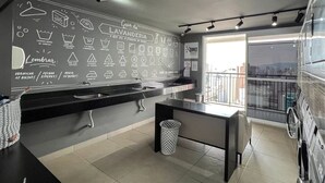 A modern kitchen with a black countertop, a sink, and a chalkboard with various icons. - Akile Central Park (São Paulo)