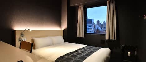 A hotel room with a bed, a desk, a telephone, a window with curtains, and a city view.