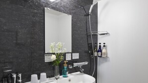 A modern bathroom with a white sink, mirror, and shower. There are toiletries on the sink and a toilet in the corner. - FL Hotel Dotonbori (Osaka)