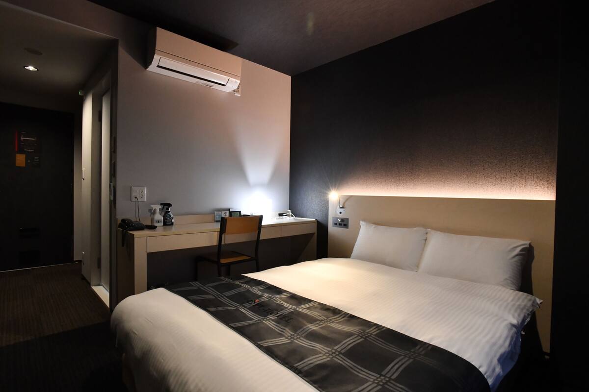 A hotel room with a bed, a desk, and a chair.