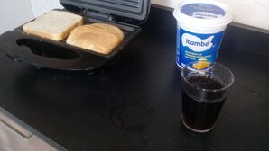 A toaster with two slices of bread, a cup of coffee, and a container of itambé drink on a kitchen counter. - Privit Studio Brazil (RJ)