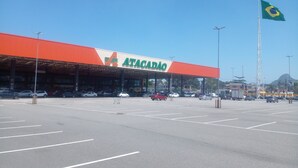 A large shopping center with a prominent Atacadão sign, multiple parking spaces, and a Brazilian flag. - Privit Studio Brazil (RJ)