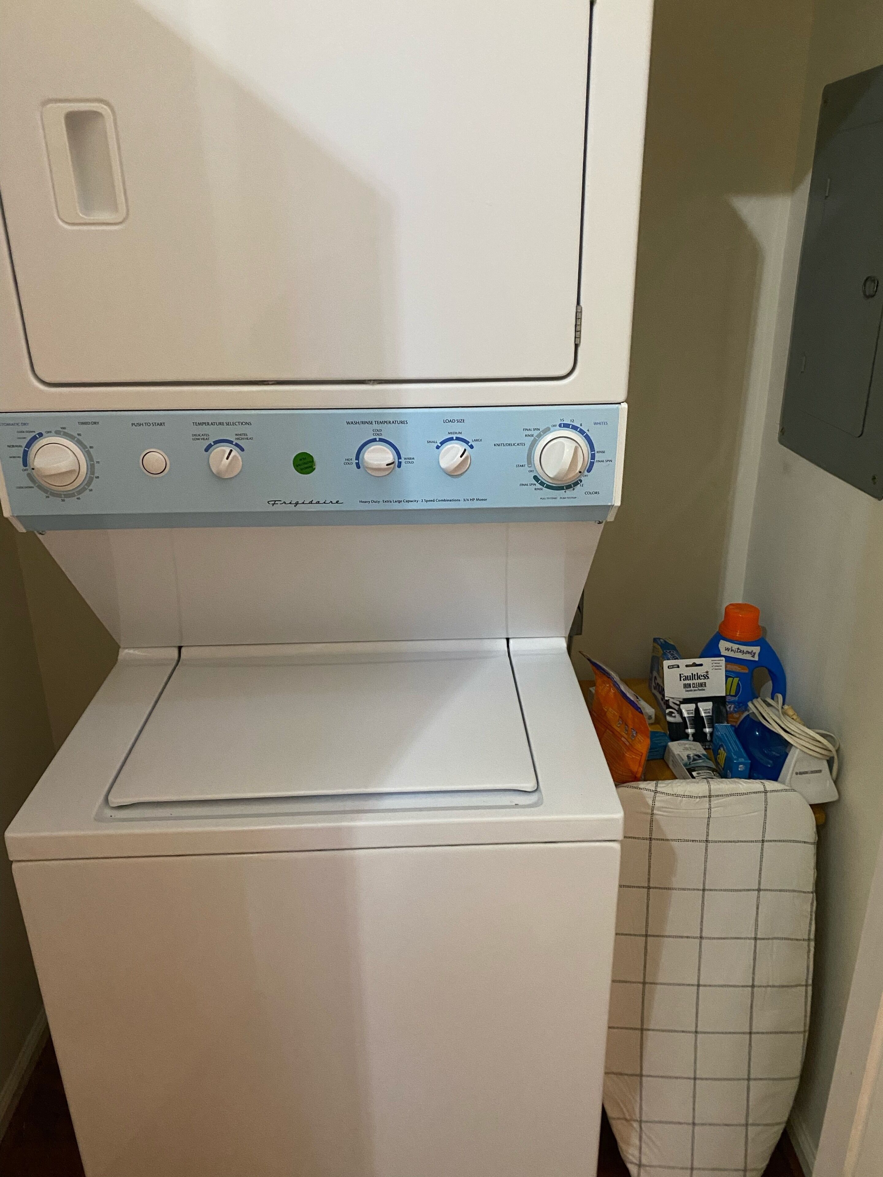 Una lavadora de carga frontal con panel de control, una cesta de ropa y productos de limpieza.