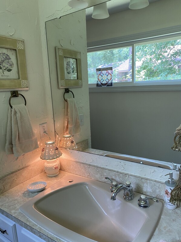 A bathroom with a large mirror, a sink, and a window with a view of trees.