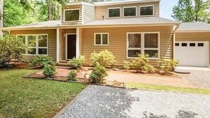 Ein zweistöckiges Haus mit Veranda, Garage und gepflegtem Rasen.
