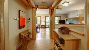 Un intérieur en bois avec un long couloir, des bancs en bois, un téléviseur et un panier posé sur une étagère.
