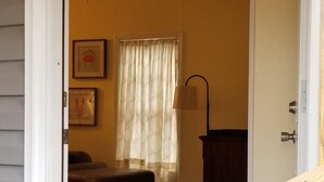 A doorway leading into a room with a wooden floor, a patterned rug, a window with sheer curtains, and a lamp. - 1/2 acre Private Fenced Dog Friendly (Navarre)