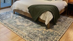 A wooden-paneled bedroom with a large bed, a nightstand, a lamp, and a view through a window. - Mountain Retreat with Hot Tub Near State Park (Golden)