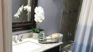 Ein Badezimmer mit Waschbecken, Spiegel, Toilette und Duschvorhang.