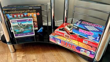 A room with a glass partition, a wooden floor, and various board games like 'Ravensburger Puzzle' and 'Boggle'.