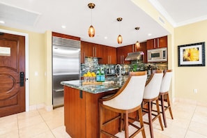 A modern kitchen with a central island, stainless steel appliances, and bar stools.