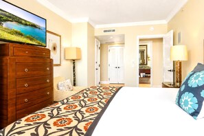 A hotel room with a bed, a dresser, a television, and a bathroom visible through an open door.