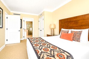 A hotel room with a bed, a nightstand, a lamp, and a door leading to a bathroom.