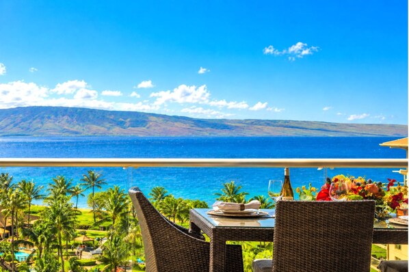 A dining table with a view of the ocean and mountains.
