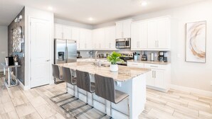 Una cocina moderna con armarios blancos, electrodomésticos de acero inoxidable y una isla de mármol.