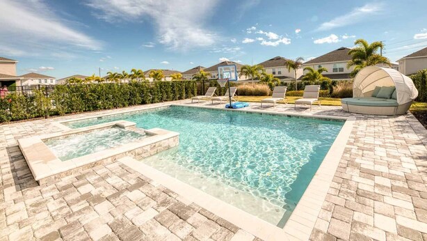 Una piscina con hidromasaje, sillas de descanso y una zona de estar cubierta.