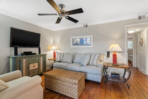 Relax in this inviting living room with a flat-screen TV, comfortable sofa, and a cozy ottoman.