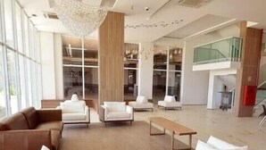 Eine großzügige Lobby mit einem modernen Sofa, weißen Sessel und einem Holztisch.