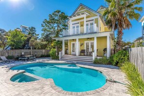 Une maison à deux étages avec une piscine, une véranda et un jardin clôturé.