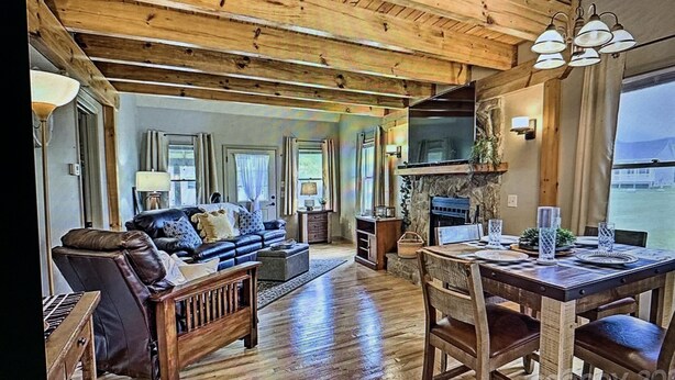 A spacious living room with a wooden ceiling, a fireplace, and a dining area with a table set for four.