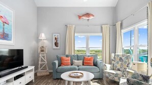 A living room with a TV, a sofa, a coffee table, and a view of the outdoors. - Bayfront 2/2 Condo w/pool & Pier! Weekly Discounts (Rockport)