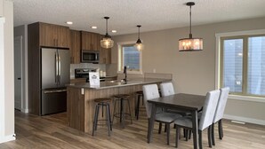 A modern kitchen with wooden cabinets, stainless steel appliances, and a central island with bar stools.