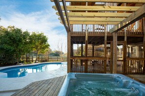 Una terraza de madera con un jacuzzi y una piscina.