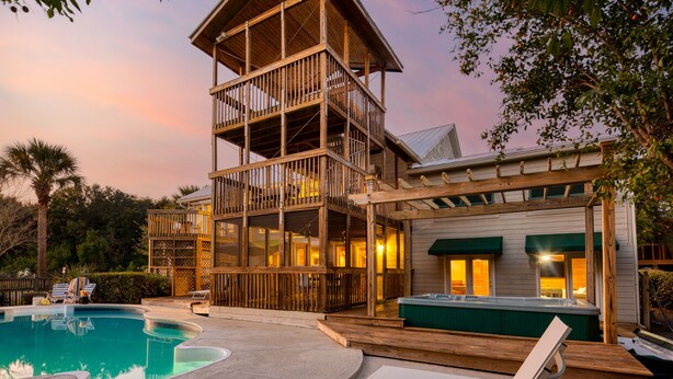 Una estructura de madera de dos pisos con balcón, piscina y jacuzzi.