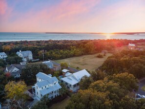 Un área residencial costera con casas, cielo despejado y un atardecer sobre el océano.