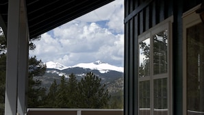 Vista de uma varanda com vista para montanhas cobertas de neve e um vale arborizado.