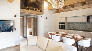 Una cocina moderna con vigas de madera, un rincón de comedor con sofá blanco y un cuadro grande en la pared.