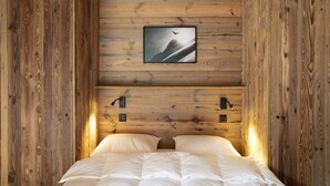 Una habitación de cabaña de madera con una cama, un cuadro en la pared y dos luces fijadas a la pared.