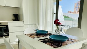 Een moderne keuken met witte kastjes, een koffiezetapparaat en een eettafel gedekt met blauwe kommen en een wijnglas.