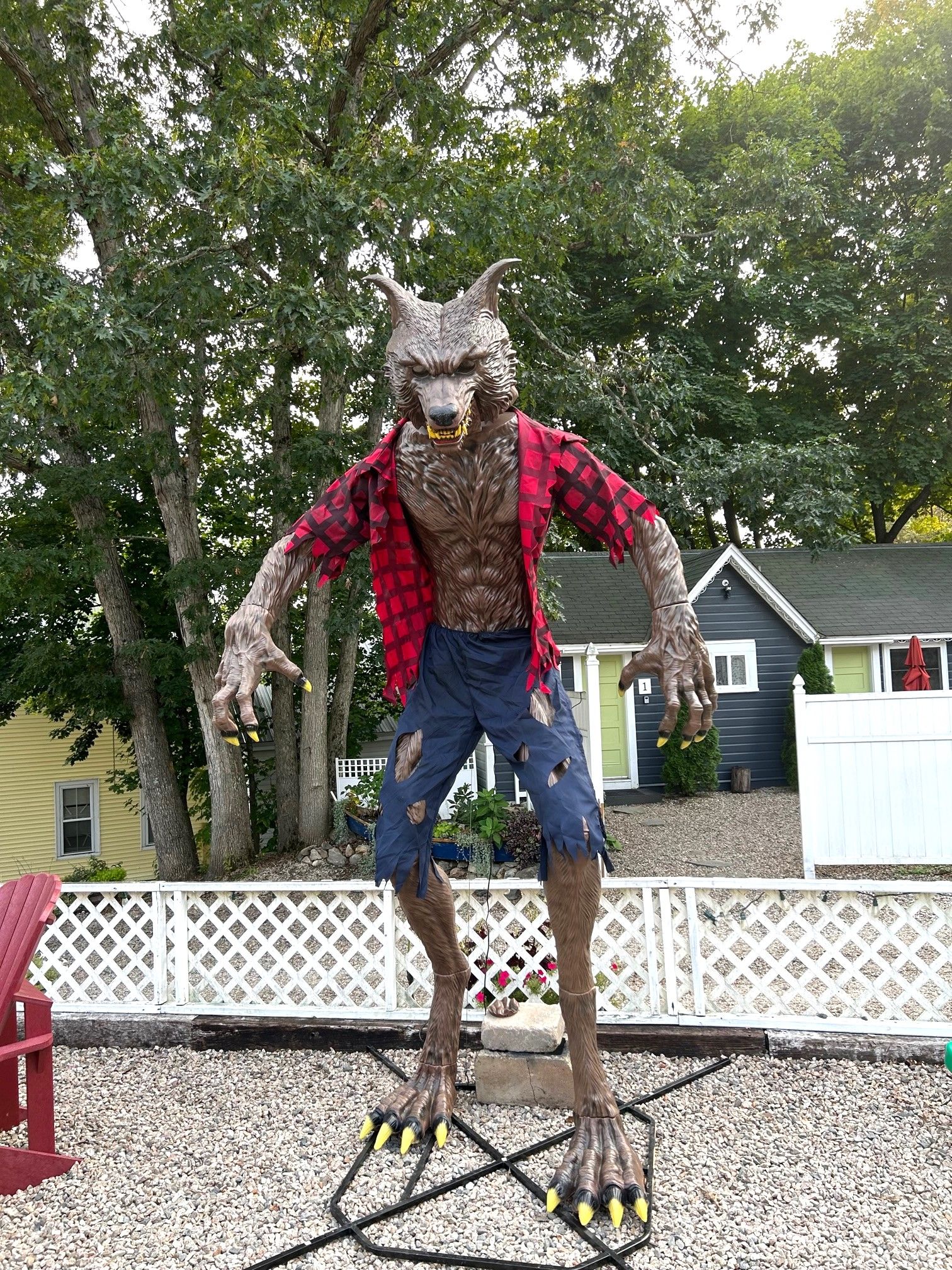 A statue of a creature with a wolf-like head, wearing a red and black checkered shirt, standing on a metal platform.