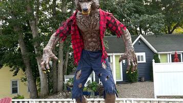 A statue of a creature with a wolf-like head, wearing a red and black checkered shirt, standing on a metal platform.