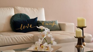 A living room with a white sofa, a green and blue pillow, a glass coffee table, and a candle holder with a candle. - Apartment with 2 bedrooms, balcony and river view - 4th floor Registration no. 5848/AL (Porto)