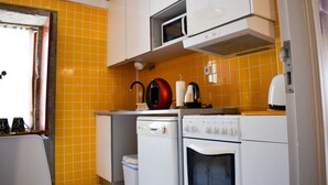 A compact kitchen with a microwave, stove, and washing machine. - Apartment with 2 bedrooms, balcony and river view - 4th floor Registration no. 5848/AL (Porto)