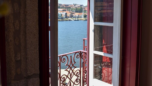 A view from a room with a window overlooking a body of water and a distant town. - Apartment with 2 bedrooms, balcony and river view - 4th floor Registration no. 5848/AL (Porto)