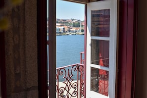 A view from a room with a window overlooking a body of water and a distant town.