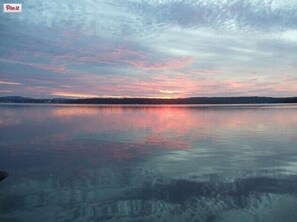 En stilla sjö vid solnedgången, med en klar himmel och en avlägsen strandlinje.